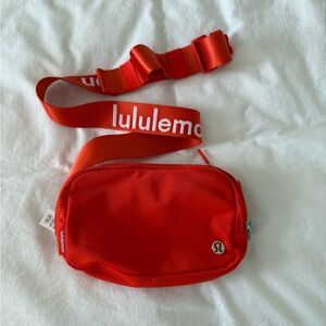orange ish red lululemon belt bag, wording on the strap